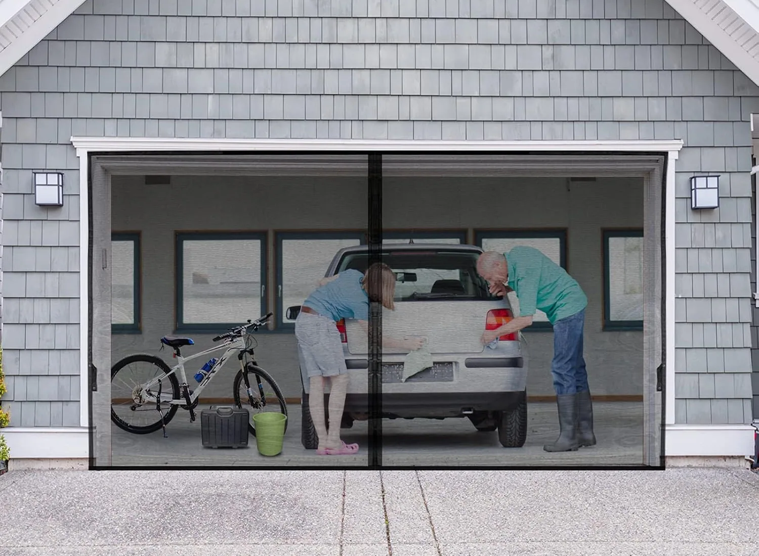 Two people washing a car in a garage behind a closed FEGO garage door screen