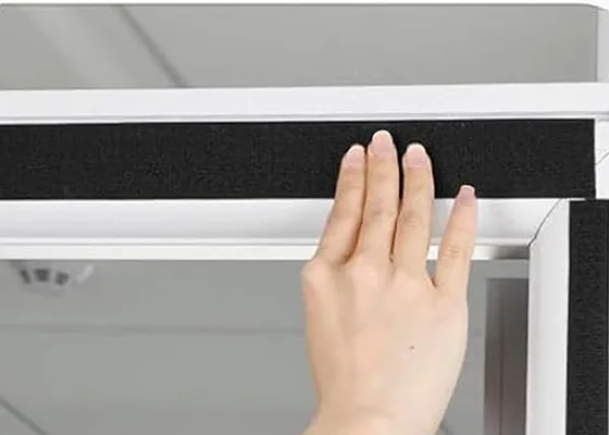 A hand pressing the adhesive hook-and-loop strip onto a door frame