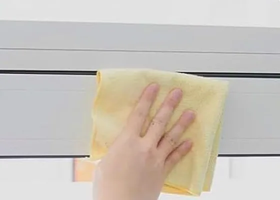 A hand wiping a garage door frame with a cloth before the strip goes on